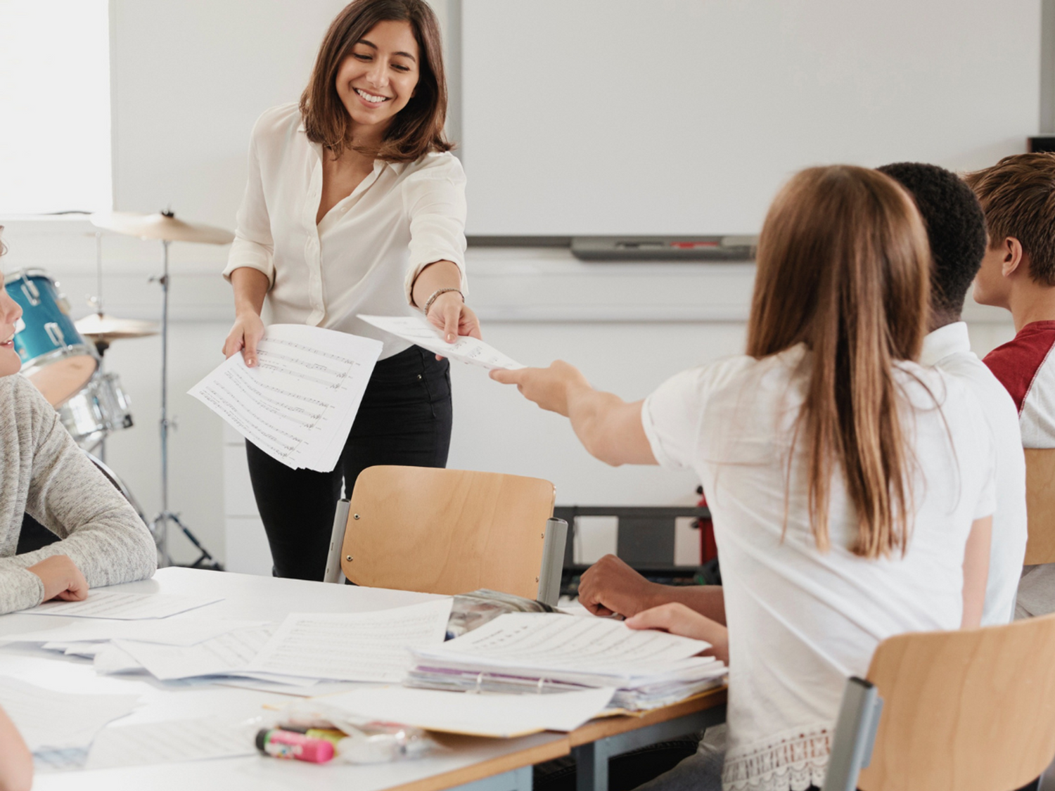 A teacher handing out work to students in a classroom