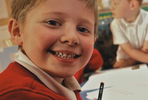 A learner at Wygate Park Academy smiling at the camera, improving their literacy in KS2.
