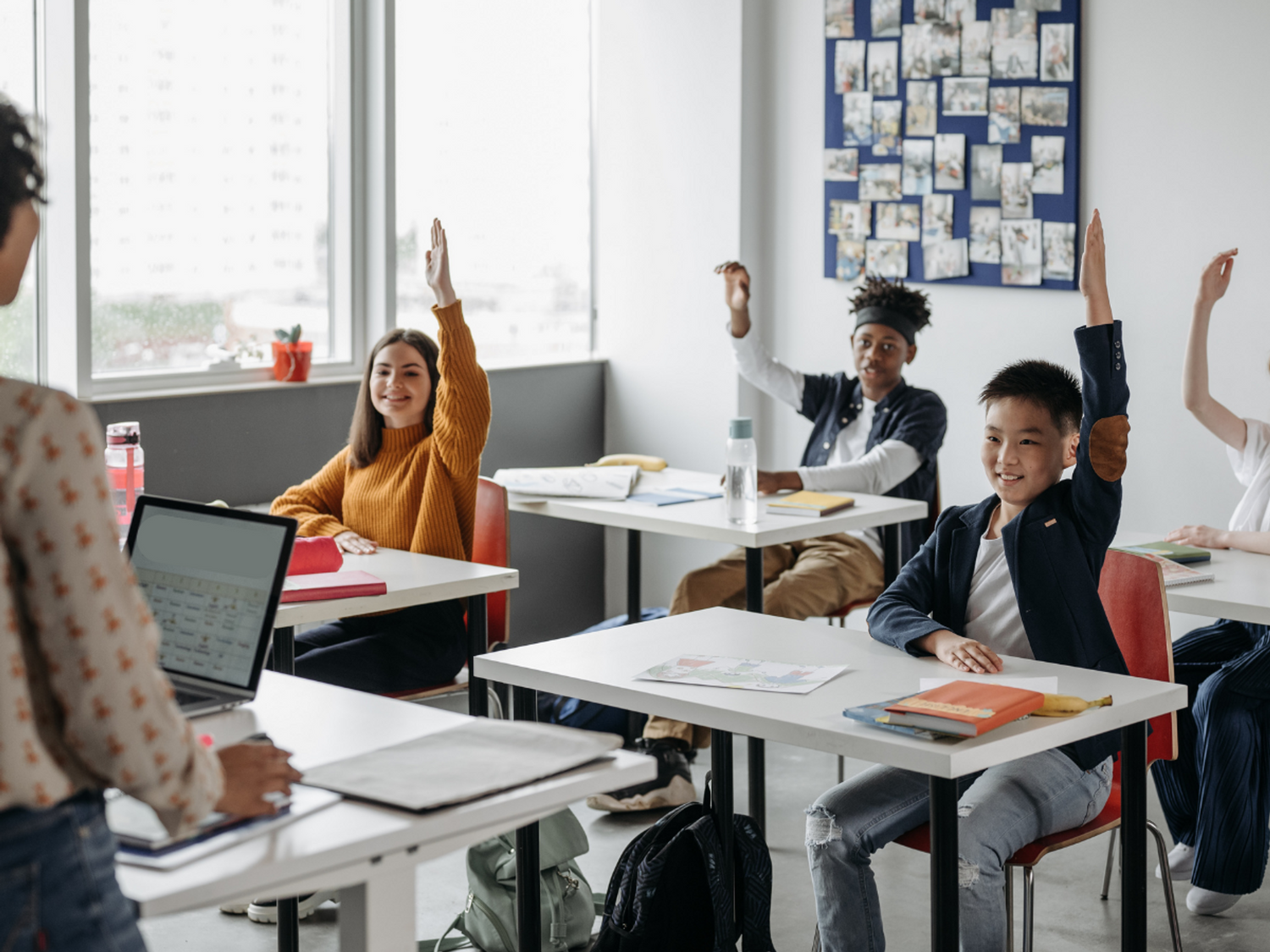 Children putting their hands up in the classroom.