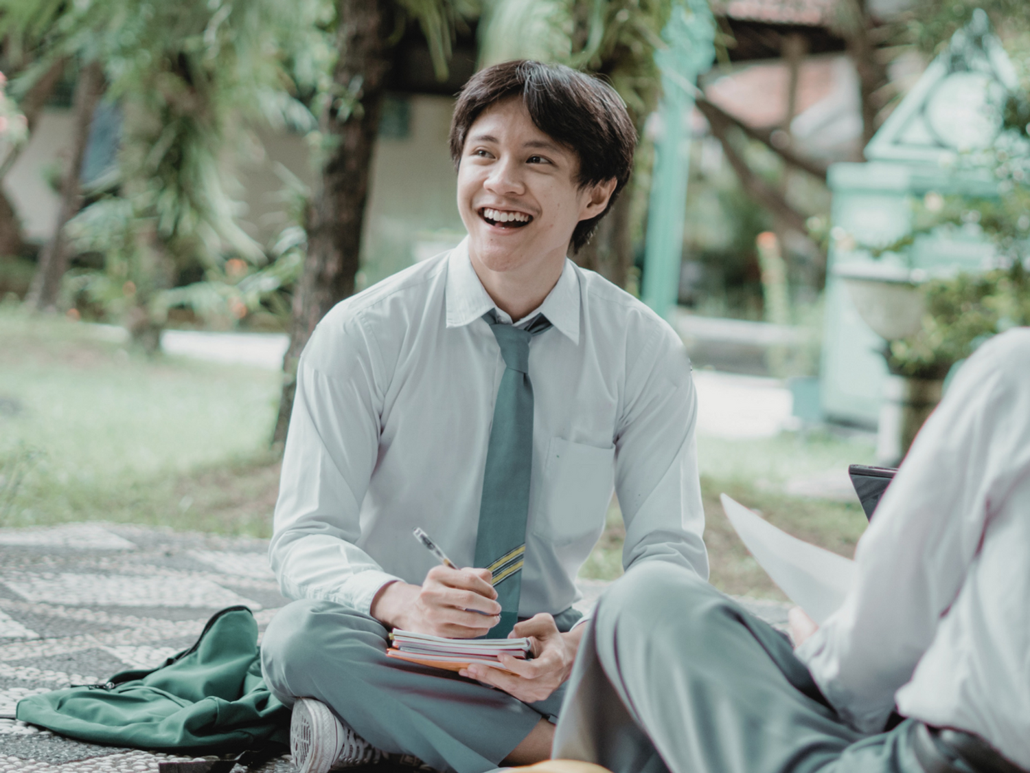 A boy in a school uniform doing work.