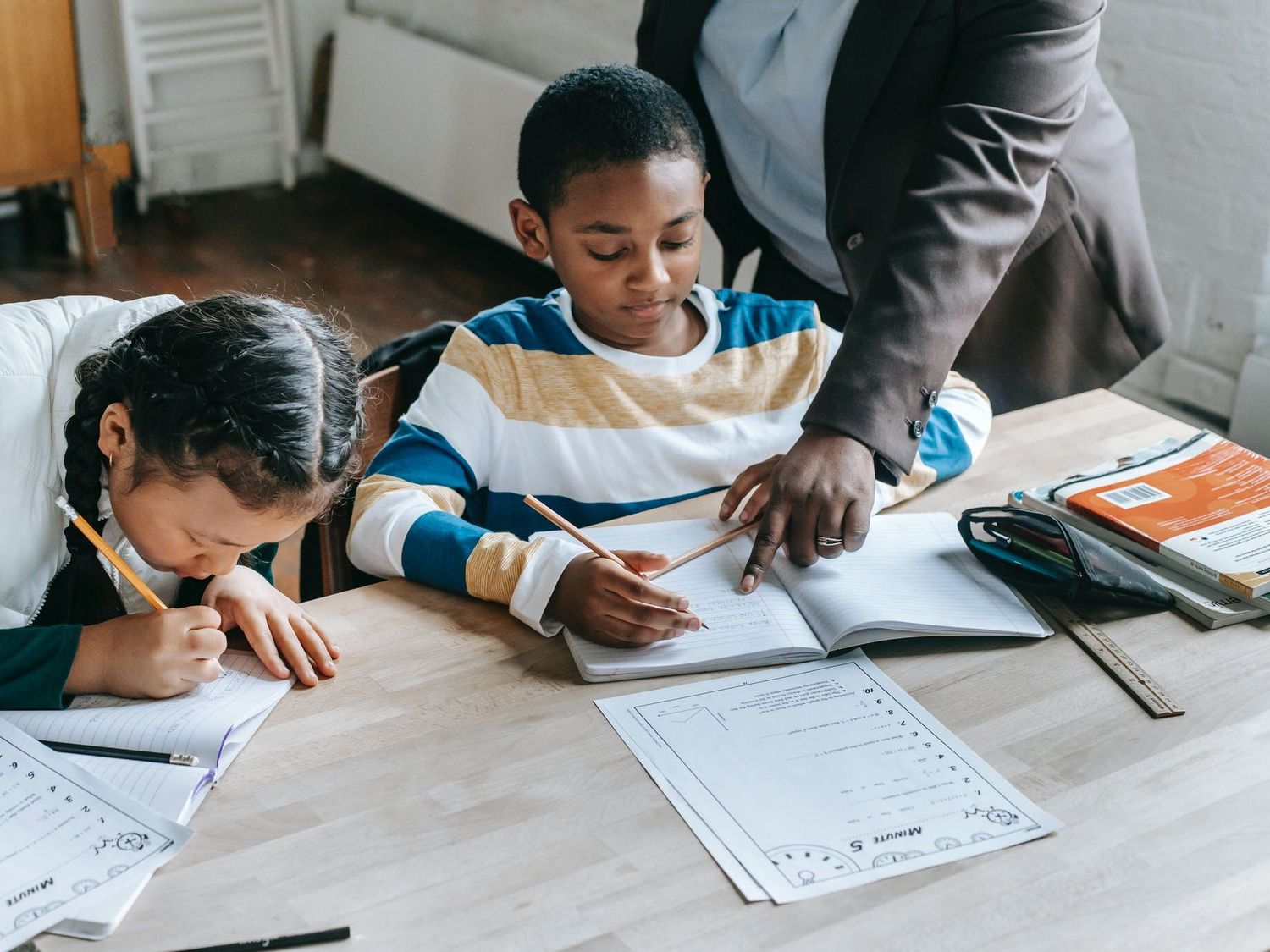 A teacher helping two students work on their literacy