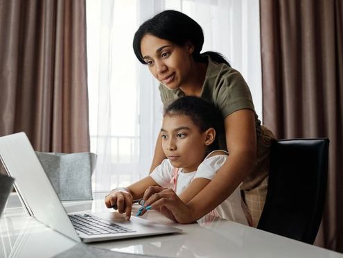 A parent and child learning together on a laptop