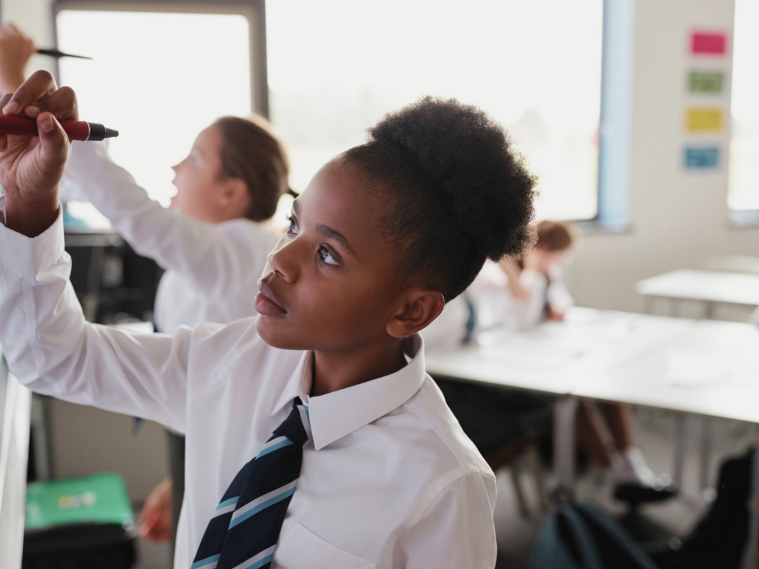 A student writing on a whiteboard in a classroom