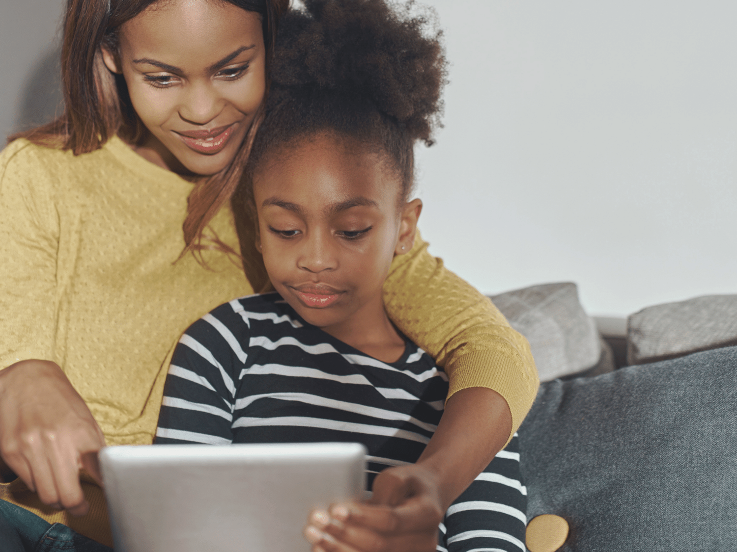 A mother and child working together on an iPad.