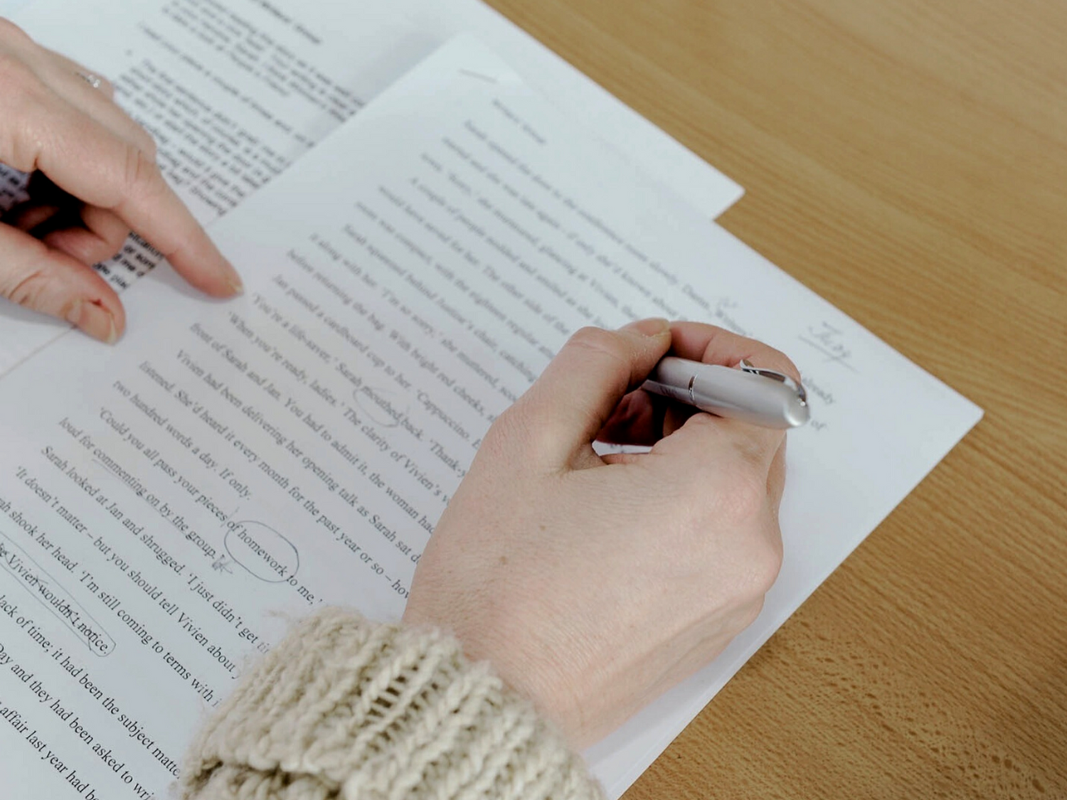 Hands holding a pen and writing on a desk