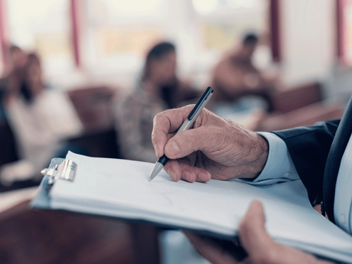 A teacher writing while watching a class of students