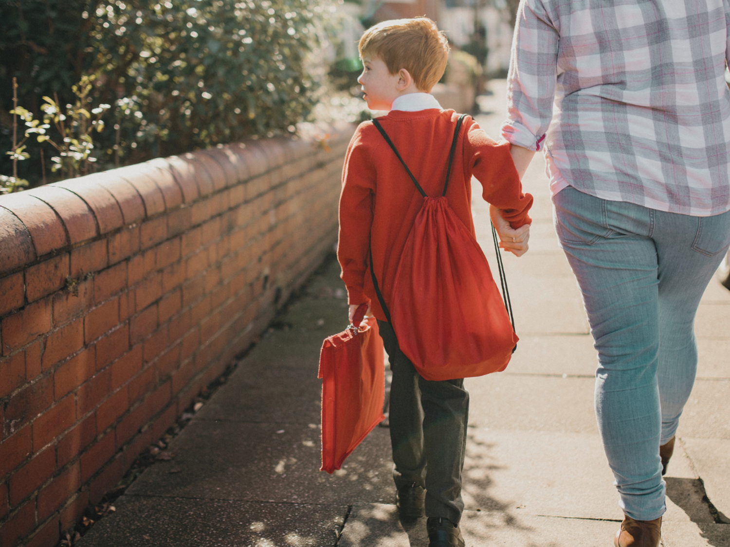 A child walking to school hand in hand with his mother.